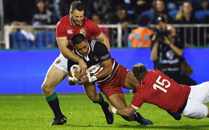 NZ Barbarian player Sam Vaka is tackled by Lions players.