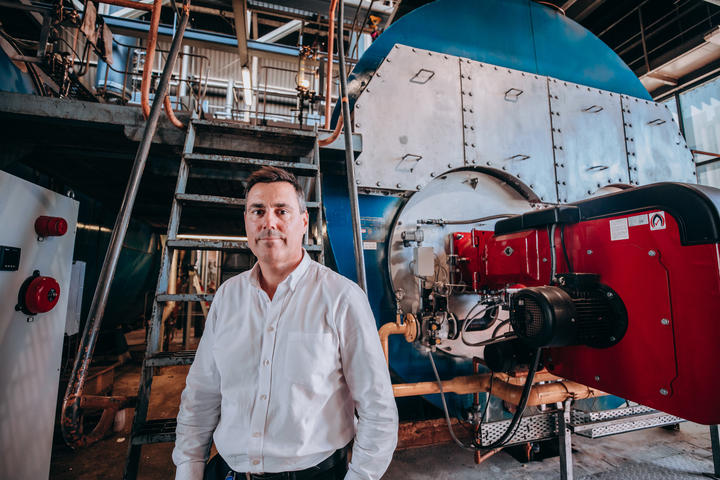 Man stands in front of boiler that is almost to the ceiling 