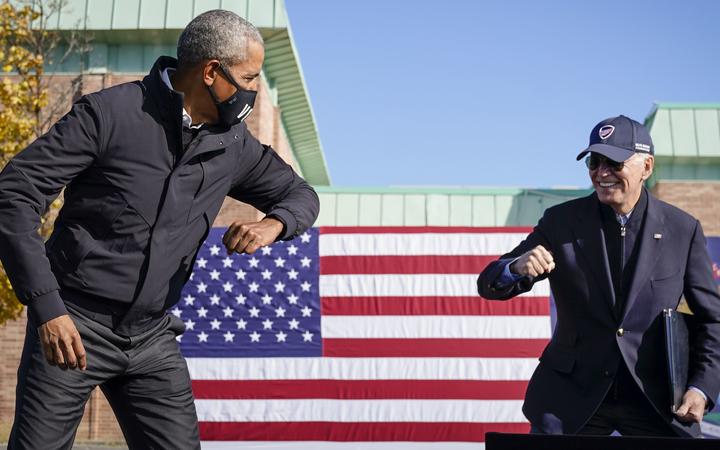 FLINT, MI - OCTOBER 31: Former U.S. President Barack Obama and Democratic presidential nominee Joe Biden greet each other with a socially distant "air" elbow bump at the end of a drive-in campaign rally at Northwestern High School on October 31, 2020 in Flint, Michigan. 