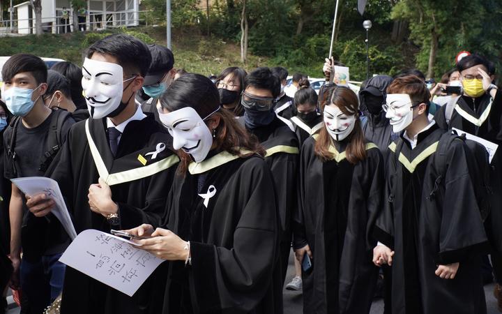 Students from the Chinese University of Hong Kong (CUHK), wearing graduation gowns and and masks, take part in a protest march in memory of the pro-democracy demonstrations at CUHK a year ago, in the Shatin area of Hong Kong on November 19, 2020.