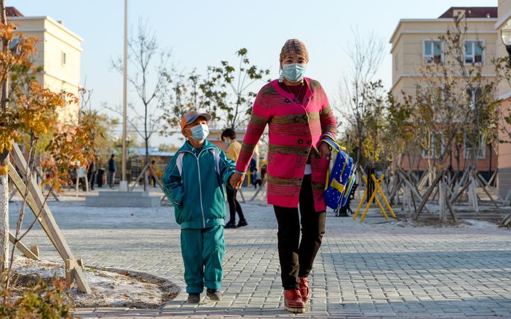 A woman and her child are on the way to their new house in Axili Town of Changji, northwest China's Xinjiang Uygur Autonomous Region, Oct. 16, 2020. 