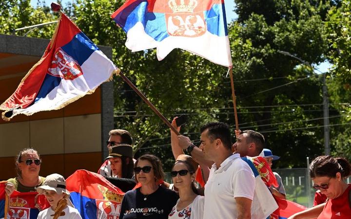 Supporters of Serbian's tennis player Novak Djokovic hold national flags as they gather in front of Federal Court building during his hearing in Melbourne on January 16, 2022.