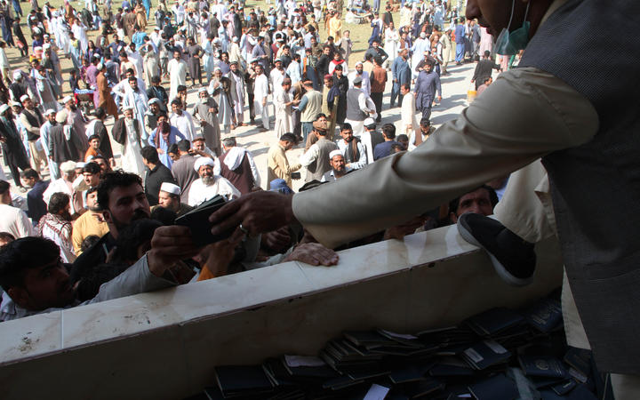 Afghans gather to collect token needed to apply for visas to Pakistan near the Pakistani consulate at an open stadium in Jalalabad city, Afghanistan.