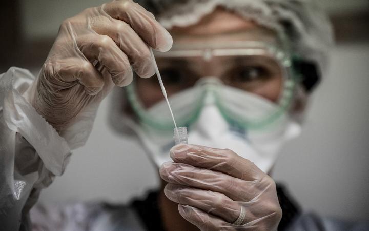 (FILES) In this file photo taken on September 22, 2020 A medical assistant takes a sample from a patient for a coronavirus (Covid-19) test at an analysis laboratory in Le Peage-de-Roussillon, some 30kms south of Lyon, south-eastern France. 