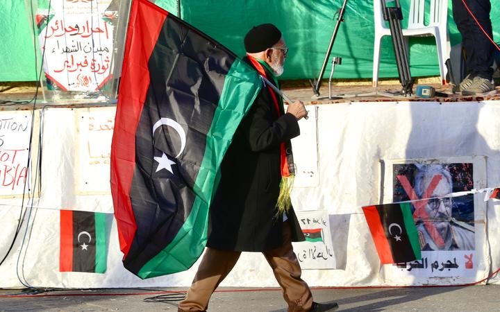 An old man carries a flag of Libya during a protest against the attacks and ceasefire violations in Tripoli on January 24, 2020.