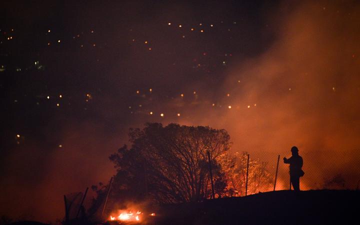 Firefighters position in a residential area and monitor flames climbing a ridge toward homes at the Blue Ridge Fire in Yorba Linda, California.