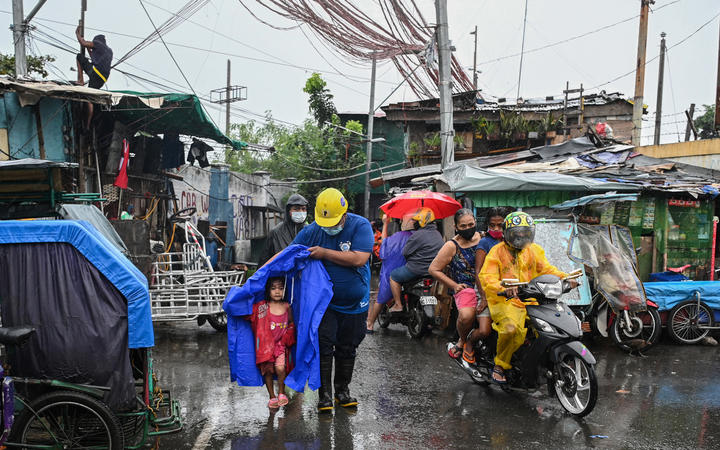 A rescue worker escorts a child to a waiting vehicle during an evacuation of informal settlers living along coastal areas in Manila 