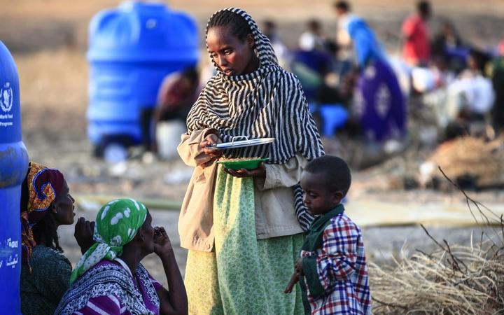 An Ethiopian refugee who fled intense fighting in their homeland of Tigray, speaks to a fellow refugee at the border reception centre of Hamdiyet, in the eastern Sudanese state of Kasala, on November 14, 2020.