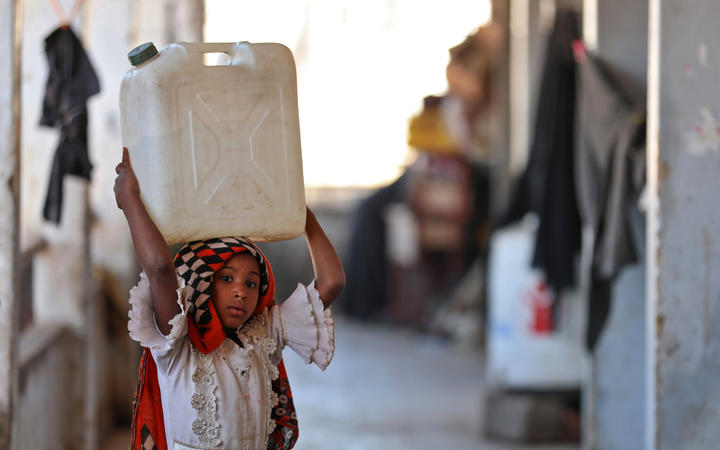 A girl carries a water container on her head at a school building for displaced Yemenis in the town of al-Turba in Taez on February 4, 2021.