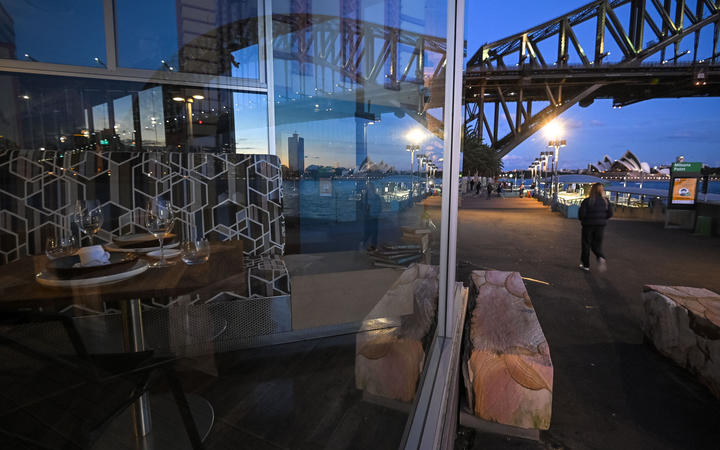 The Sydney Opera House and the Sydney Harbour Bridge are reflected in the window of a closed restaurant at Milson's Point, during lockdown in Sydney