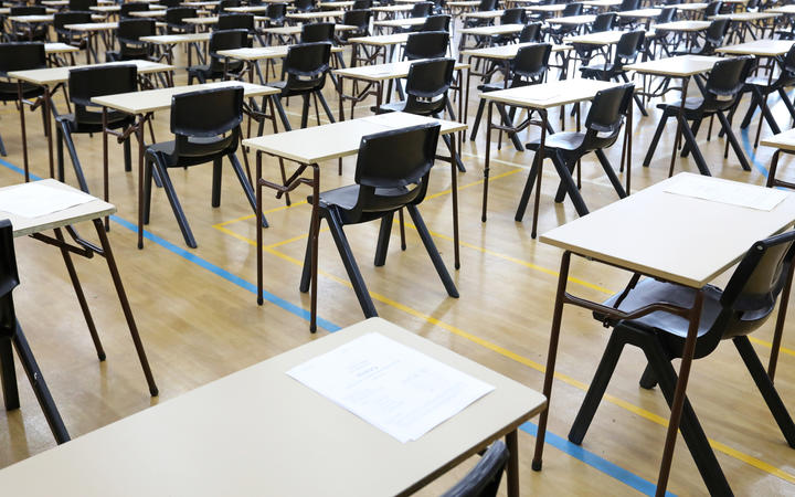 View of large exam room hall and examination desks tables lined up in rows ready for students at a high school to come and sit their exams tests papers.