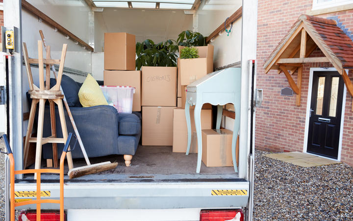 Removal Truck Waiting To Be Unloaded Outside New Home On Moving Day