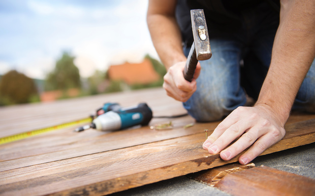 A worker hammers down timber for a house's deck. 