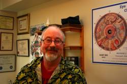 Michael the Medicine man in his clinic with his certificates and a scary poster of an iris according to iridology